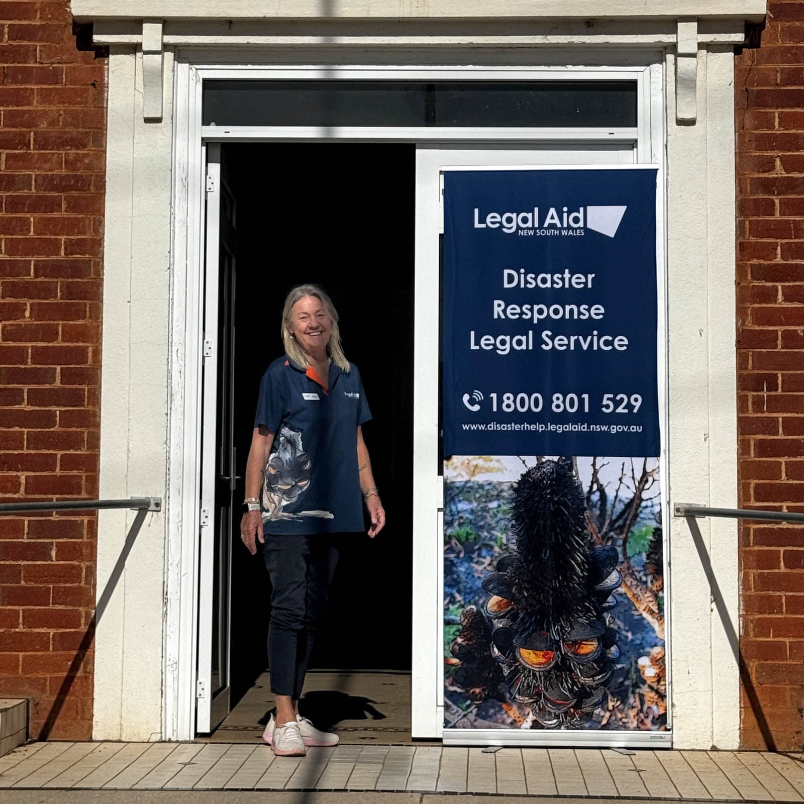 DRLS solicitor Anne Murphy Anne standing with a DRLS banner in Molong.