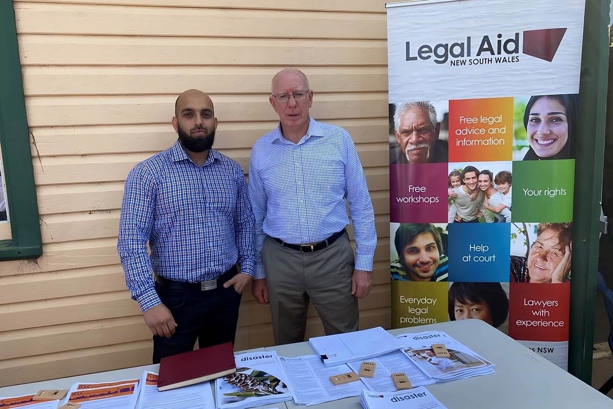 Zaky Orya and David Hurley stand next to a Legal Aid NSW banner